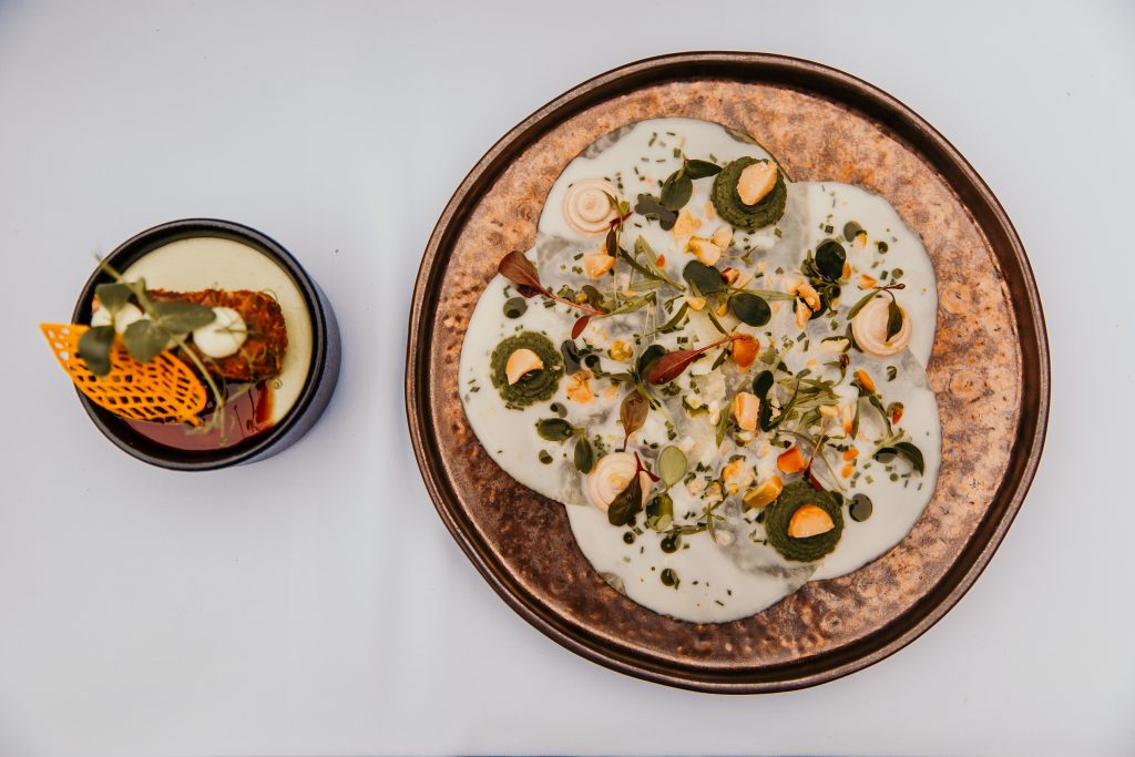 Feinschmecker-Gourmet-Gericht mit frischen Kräutern und cremiger Soße auf Keramikplatte, vegan oder vegetarisch.