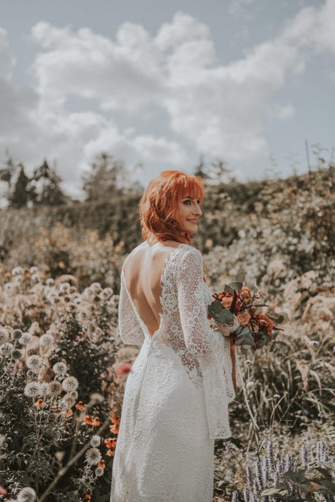 Traumhochzeit im Blumengarten, elegante Braut in Spitzenkleid mit Blumenstrau&szlig;, nat&uuml;rliche Atmosph&auml;re, romantisches Event.