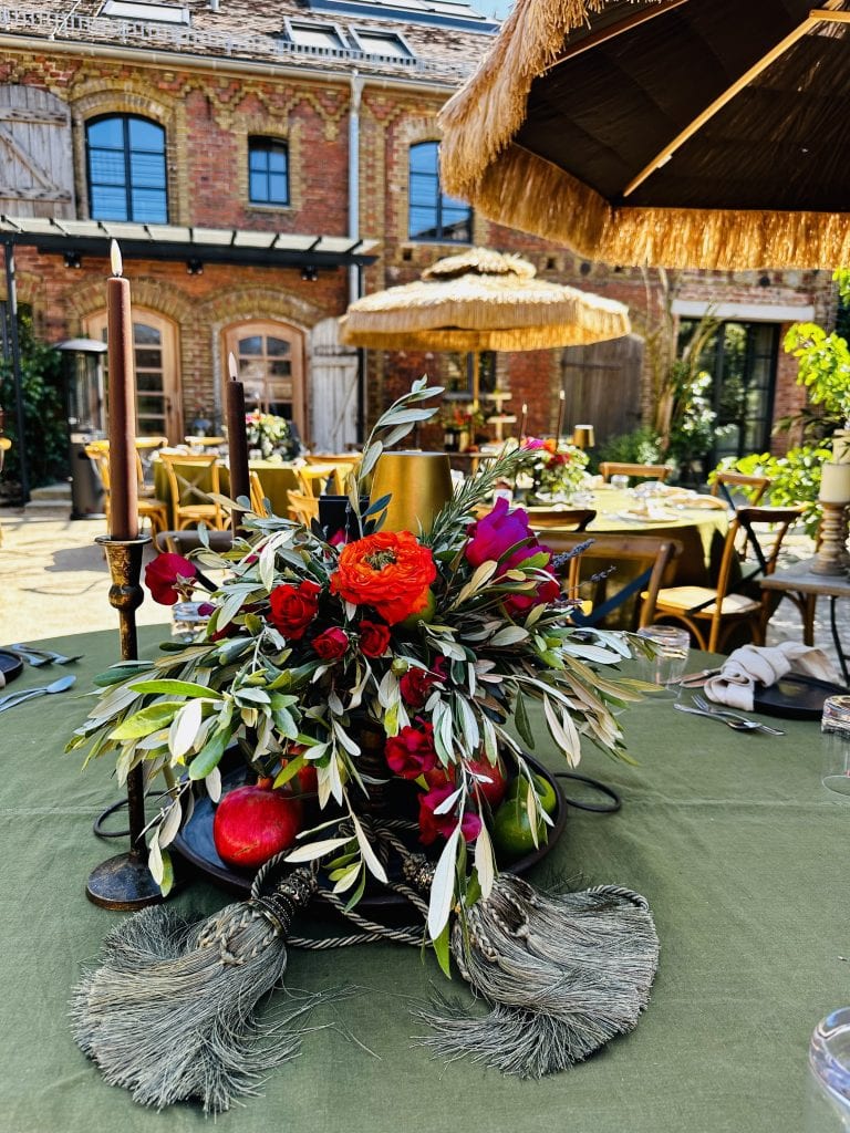 Blumenarrangement mit &Auml;pfeln auf festlicher Gartentafel bei Gut Leben Berlin.