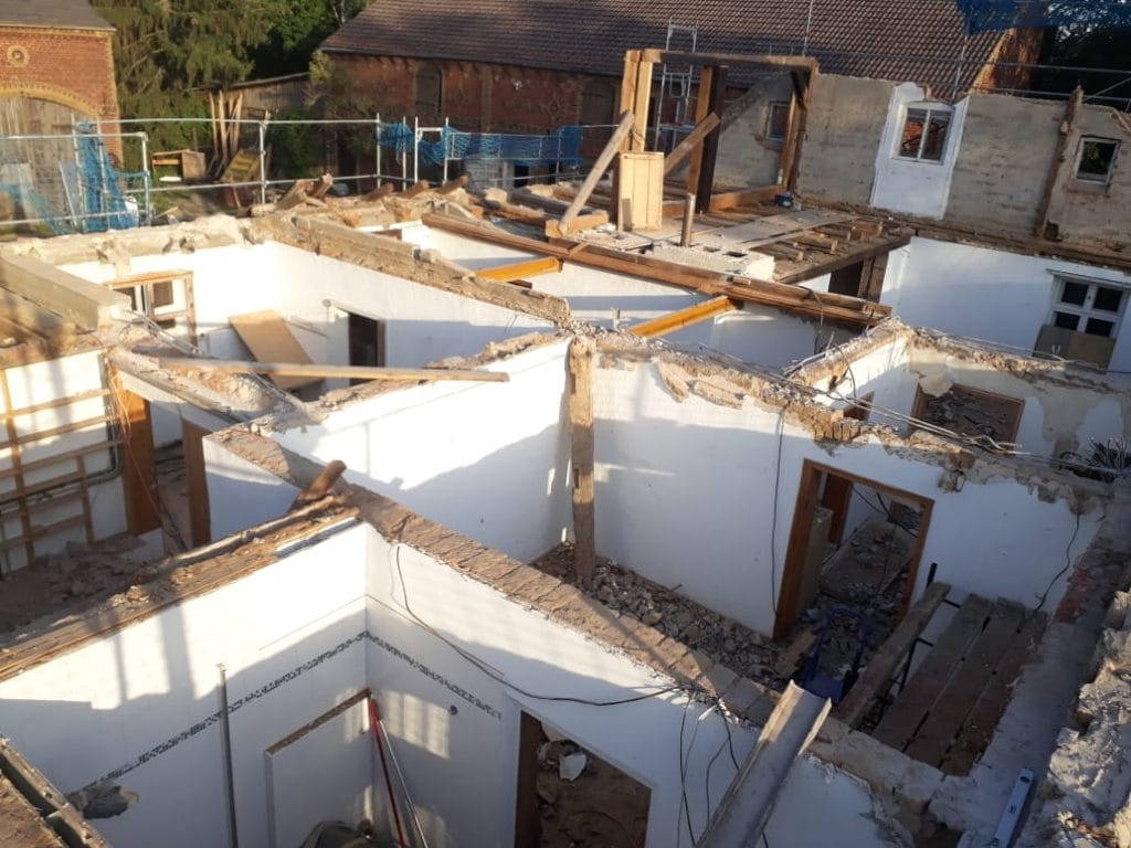 Alt text: Abbruch eines alten Hauses, Bauarbeiten im Rohbau, Baugerüst sichtbar.