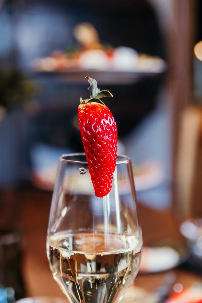 Frische Erdbeere auf einem Glas Sekt, stilvoll präsentiert, für bewusste Ernährung und Wohlbefinden.