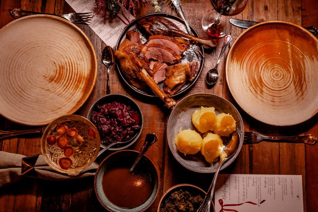 GnŃ–braten, traditionelles deutsches Gericht, serviert mit Beilagen und Rotwein bei gutem Essen.