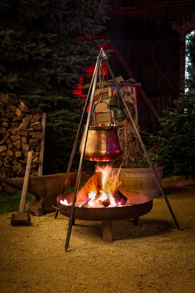 GemĂĽtliches Lagerfeuer mit Topf im winterlichen Garten bei Gut Leben Berlin.