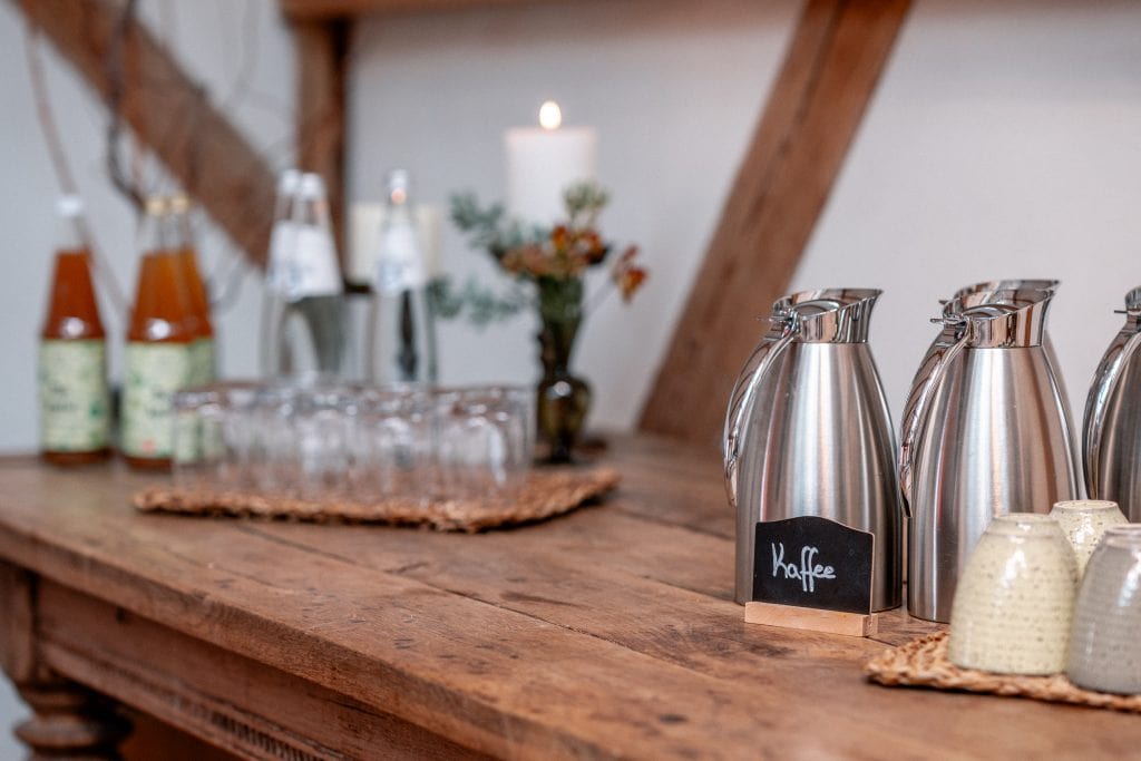 Frühstücksbereich mit Kaffee, Wasser und Säften, gemütliche Atmosphäre, natürliche Holzdekoration, Inspiration für gesunden Lebensstil.