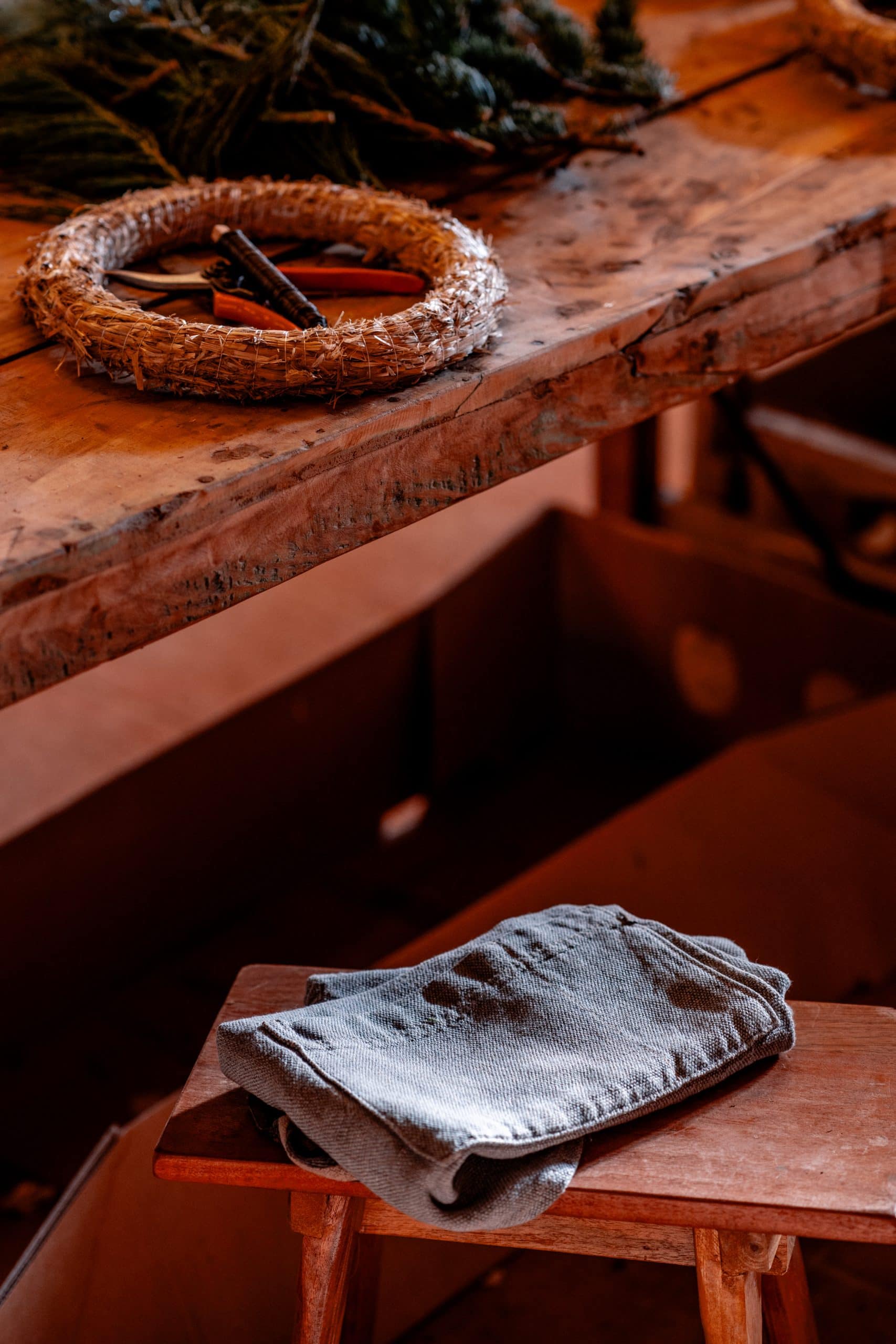 Naturholz Tisch mit Handwerkszubehör und Leinen-Handtuch, entspannte Atmosphäre für nachhaltiges Leben.