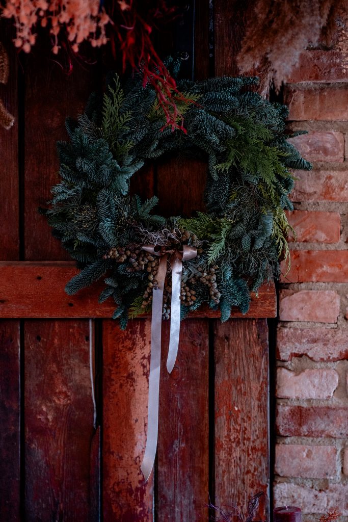 NatĂĽrlicher Weihnachtskranz aus Tannenzweigen an HolztĂĽr befestigt.