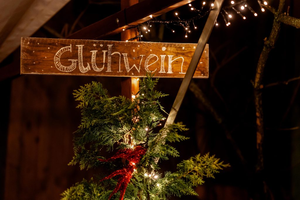 Gemütlicher Weihnachtsmarkt mit Lichterdekoration und Holzschild "Gutes Leben" in Berlin.