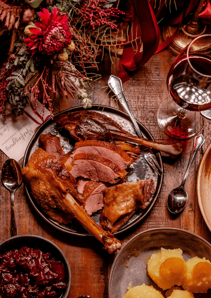 Zarte Rinderrouladen mit Rotweinsauce und Beilagen auf rustikaler Bedienungsplatte.