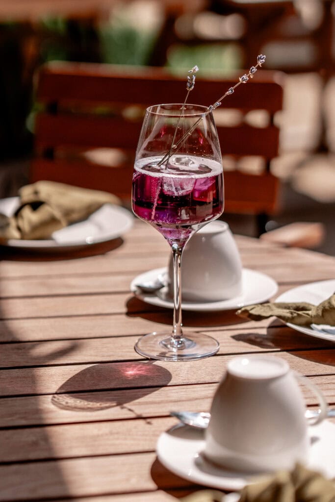 Elegantes Glas mit pinkem Getränk auf einem Holztisch im Garten.