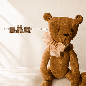 Handgefertigter brauner Teddybär mit rosa Schleife vor weißem Hintergrund.