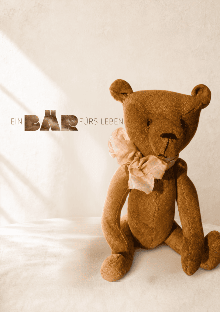 Handgefertigter brauner Teddybär mit rosa Schleife vor weißem Hintergrund.