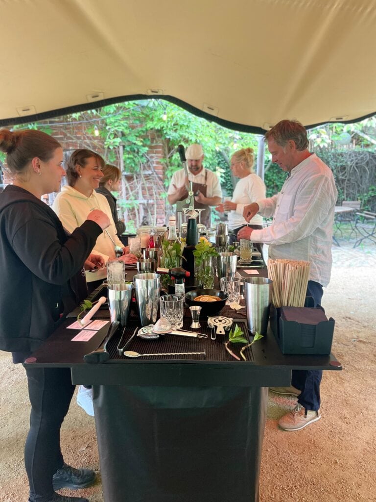 Teilnehmer beim Cocktail-Workshop im Freien unter einem Zelt bei Gut Leben Berlin.