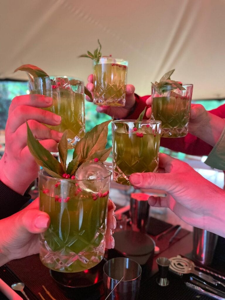 Menschen stoßen mit grünen Cocktails in Gläsern beim Workshop an.