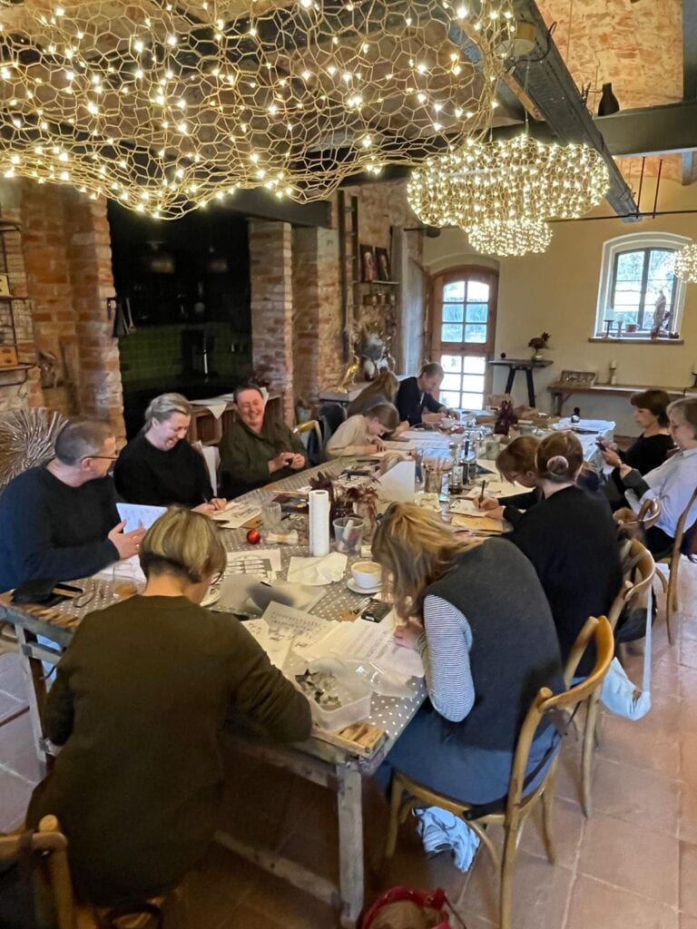 Workshop für Weihnachtskalligrafie in gemütlichem Raum mit Dekorationen und Teilnehmern.
