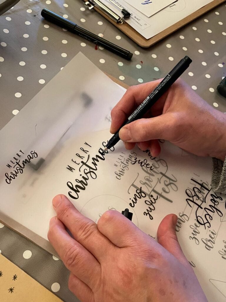 Handschriftliche Weihnachtsgrüße in kalligrafischer Schrift auf Papier.