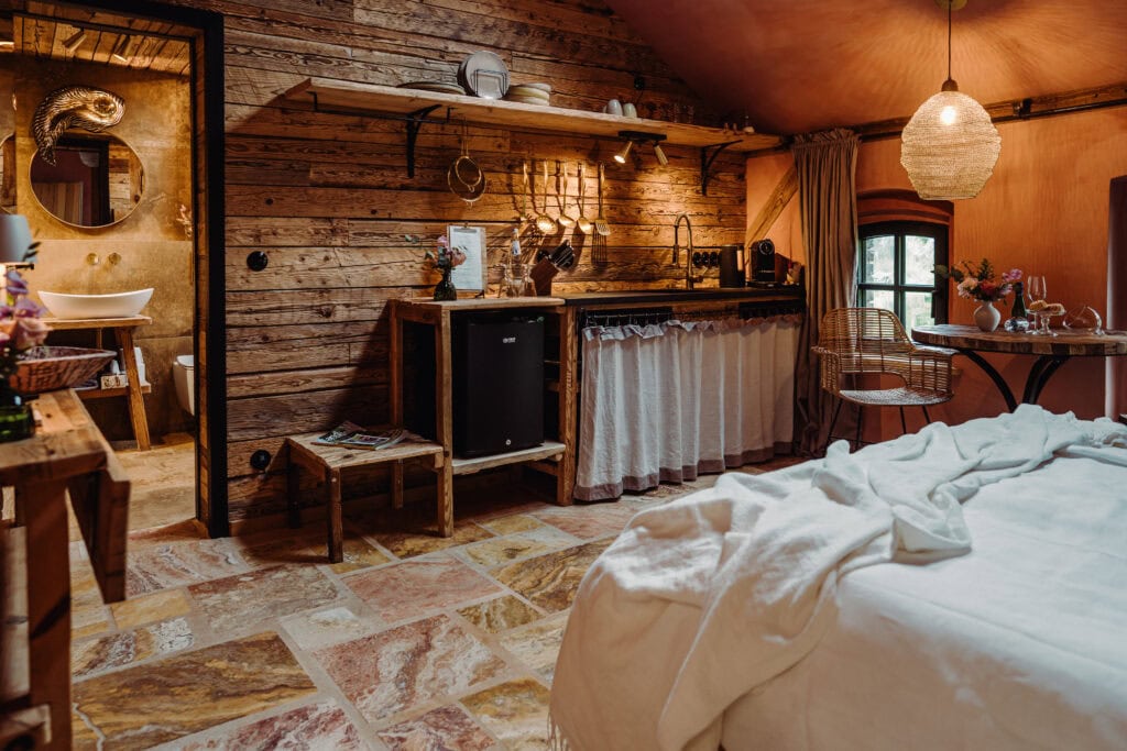 Gemütliches Schlafzimmer mit Holzdekor, Bett und Küchenbereich im Landhausstil.
