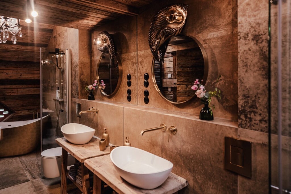 Elegantes Badezimmer mit runden Spiegeln, Natursteinwaschbecken und Dekorationen.