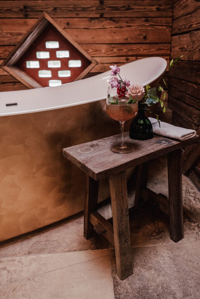 Entspannende Badewanne mit Blumen und Wein in rustikalem Badezimmer.