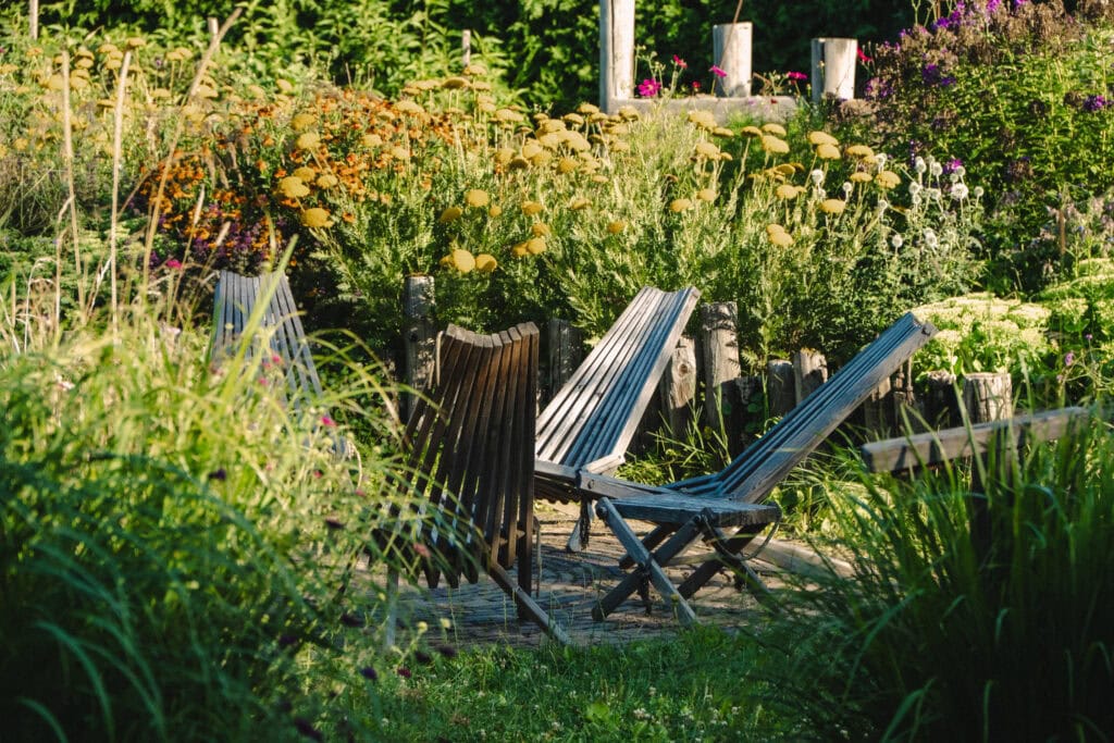 Entspannter Garten mit Liegestühlen, bunten Blumen und Natur.