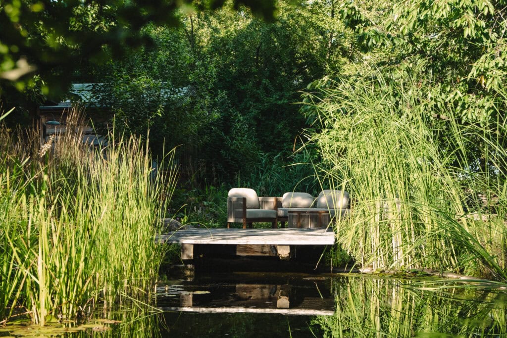Entspannender Sitzbereich am Wasser in einem grünen Garten.