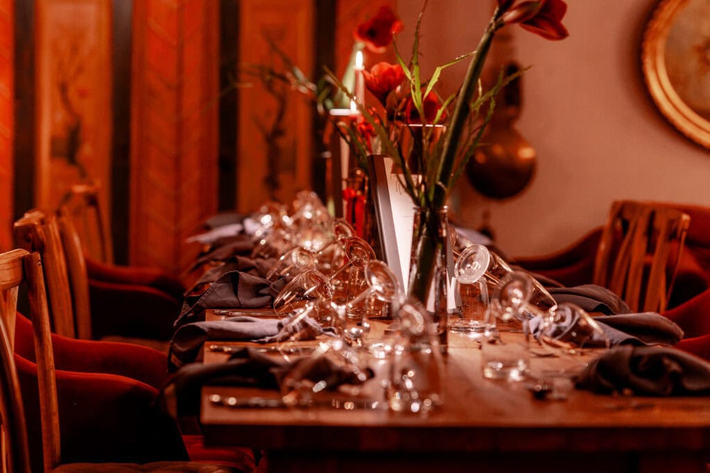 Eleganter gedeckter Tisch mit Blumen und Gläsern in gemütlichem Ambiente.