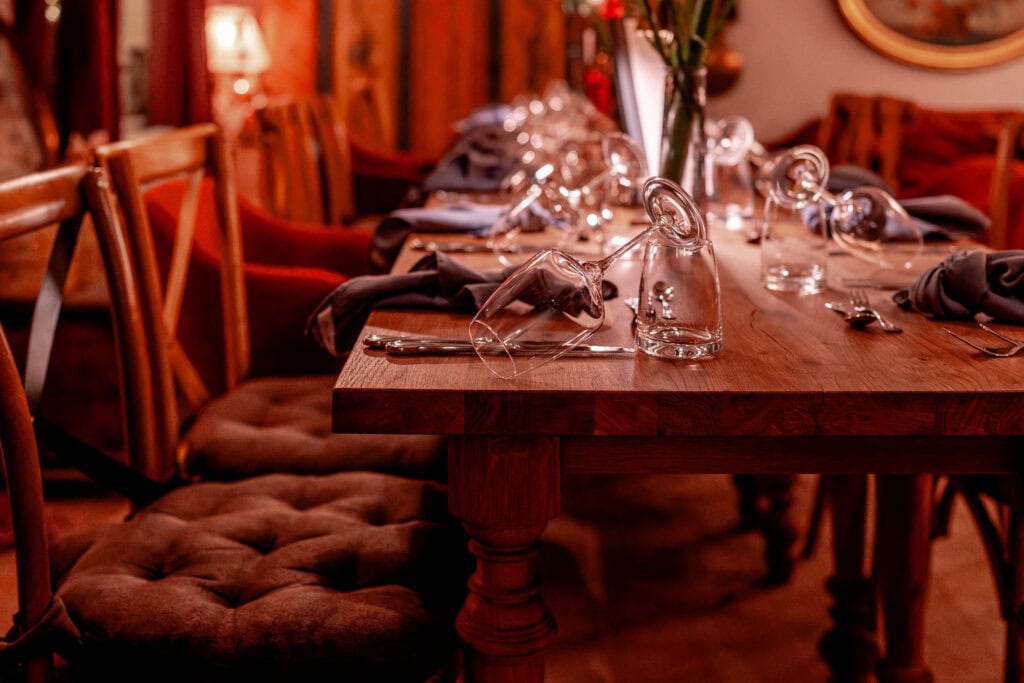 Eleganter gedeckter Tisch im rustikalen Restaurant mit Kerzen und Weingläsern.