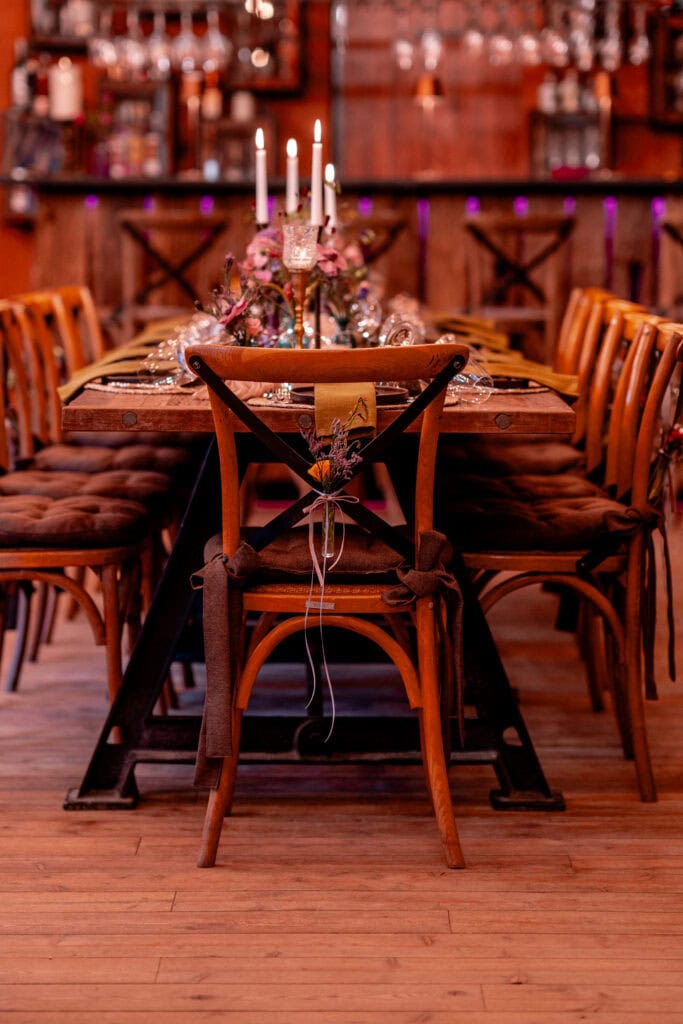 Elegant gedeckter Esstisch mit Kerzen und Blumen im rustikalen Restaurantambiente.