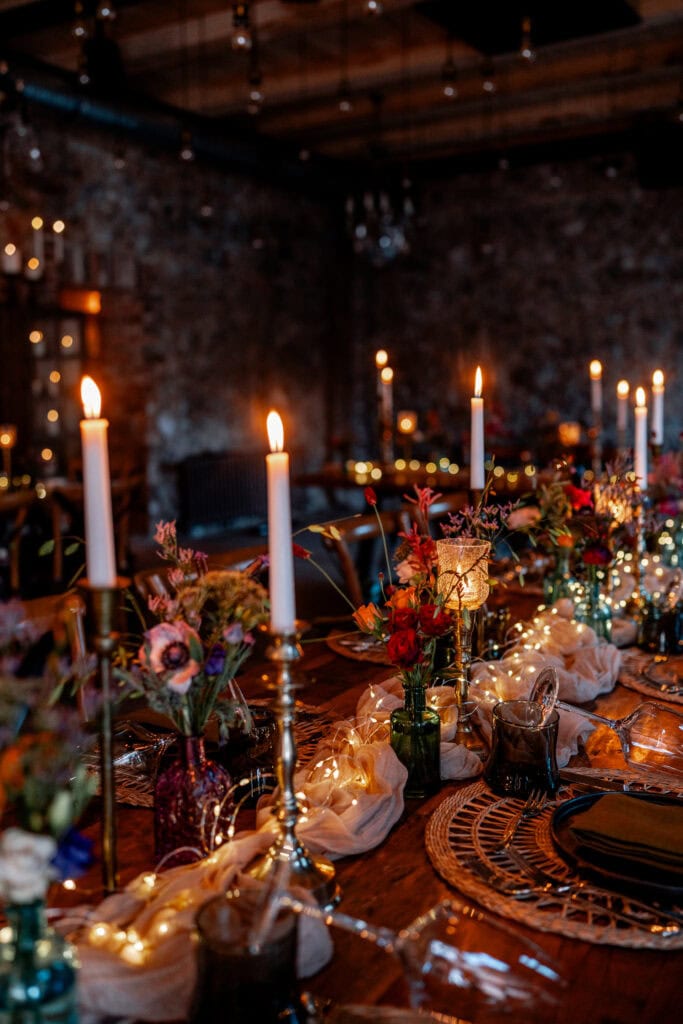 Eleganter festlicher Tisch mit Kerzen, Blumen und Lichterketten bei Gut Leben Berlin.