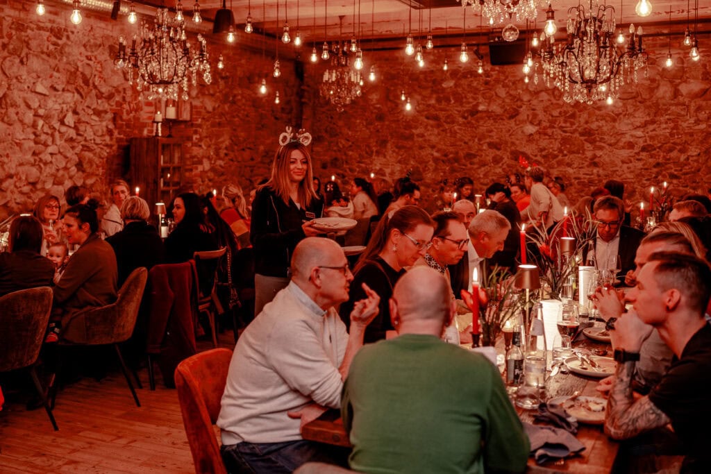 Gesellige Menschen bei einem festlichen Abendessen in einem rustikalen Restaurant mit Kerzenlicht.