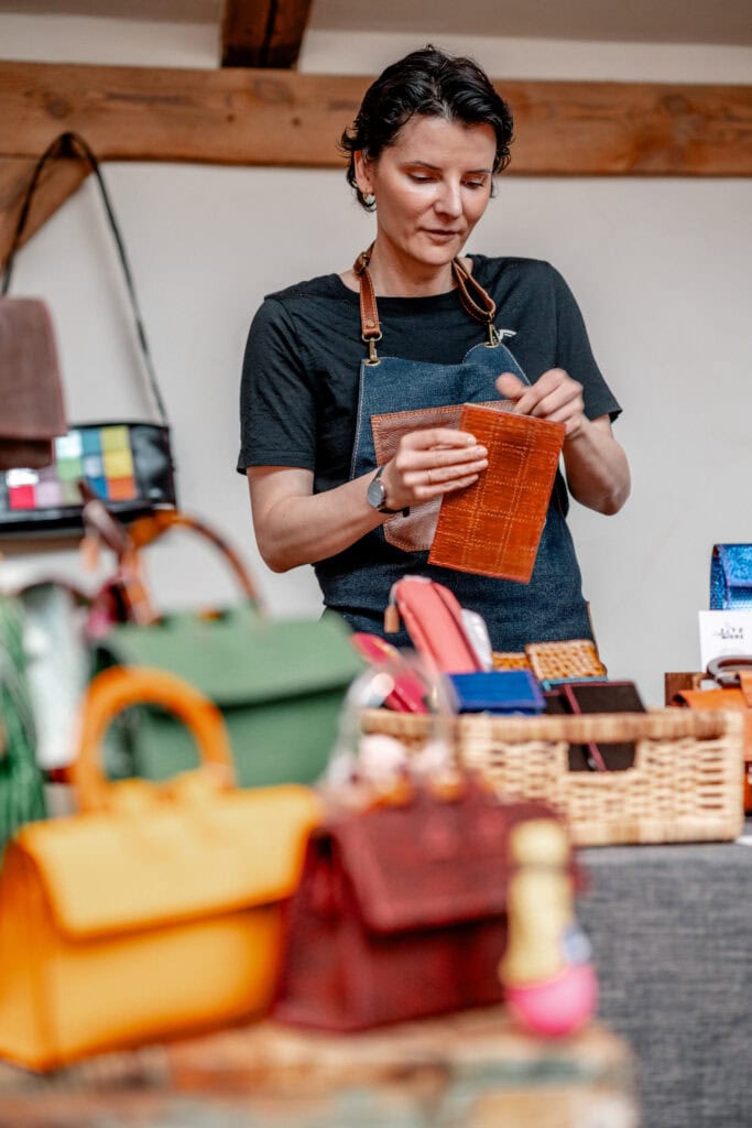 Frau beim Verkauf handgefertigter Lederwaren auf dem Markt.