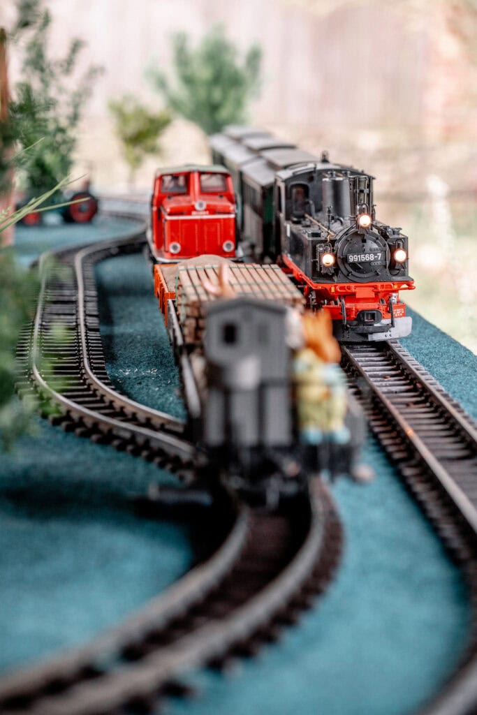 Detailaufnahme von Modellbahn mit Lokomotive und Schienen im Garten.