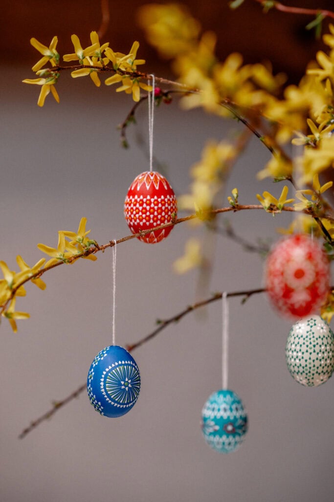 Osterdekoration mit bunten bemalten Eiern an Zweigen in Frühlingsfarbe.