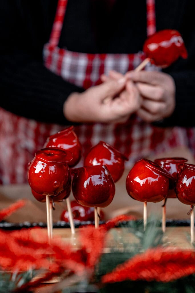Glänzende rote Äpfel auf Holzstäbchen bei Weihnachtsdekoration.