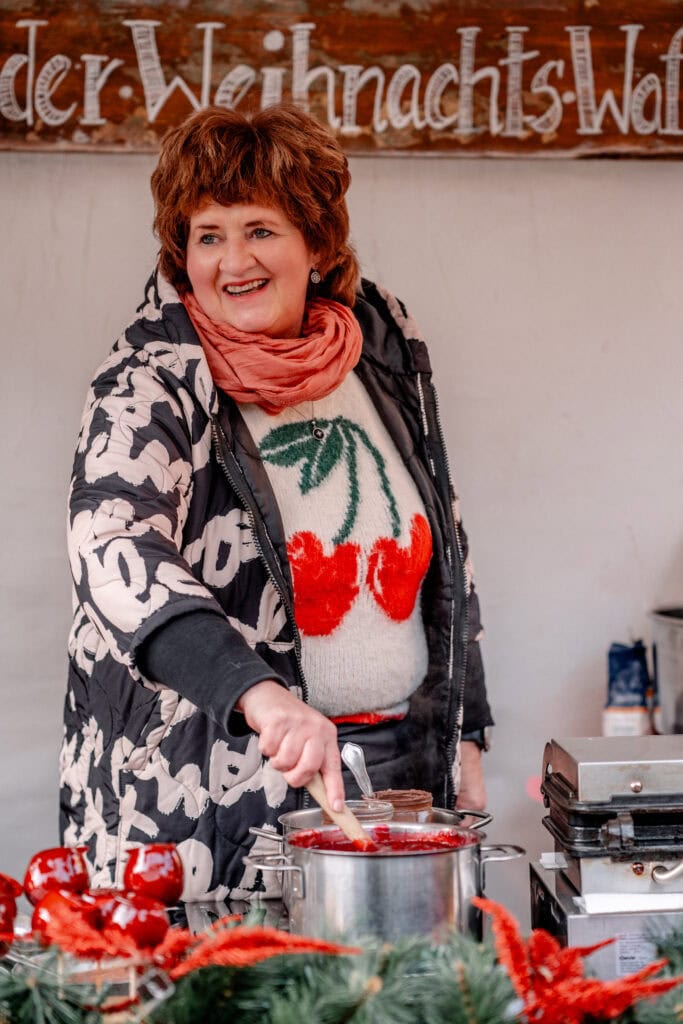 Frau beim Kochen mit Weihnachtsdekoration und festlicher Kleidung.