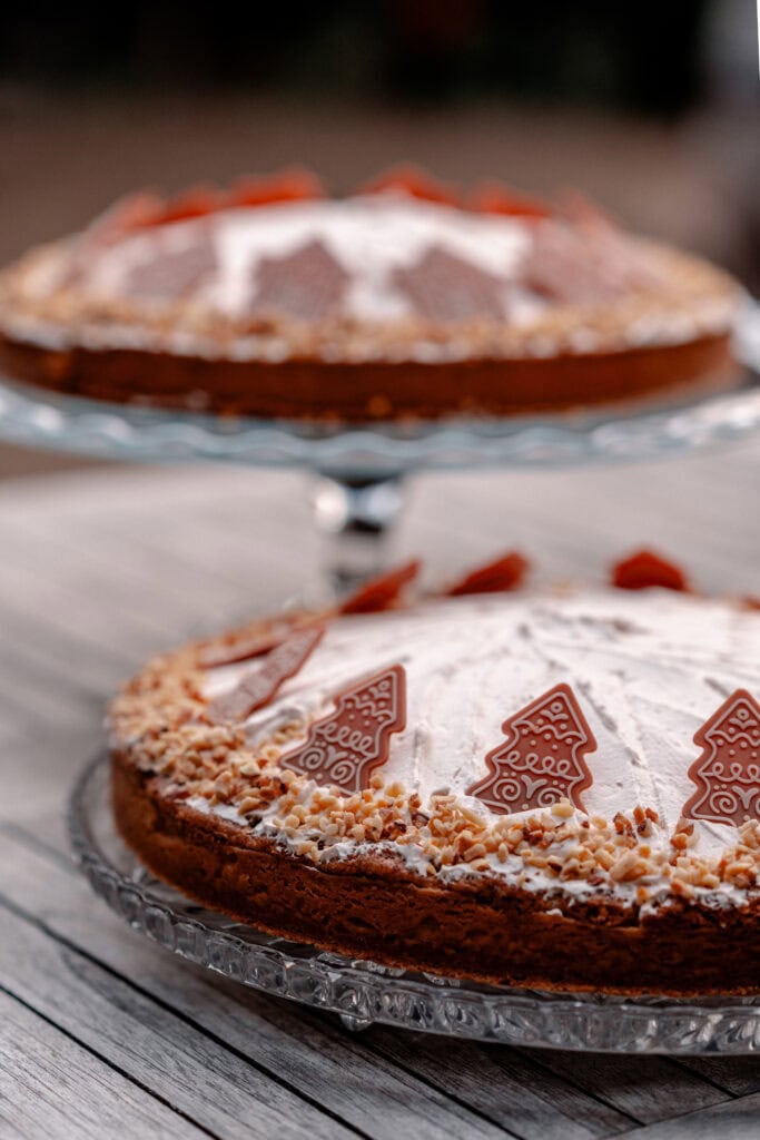 Festlicher Weihnachtskuchen mit Zuckerdekoration und Nüssen auf Holzplatte.