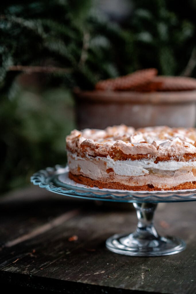 Leckere Torte auf einem Glasständer vor grüner Natur bei Gut Leben Berlin.