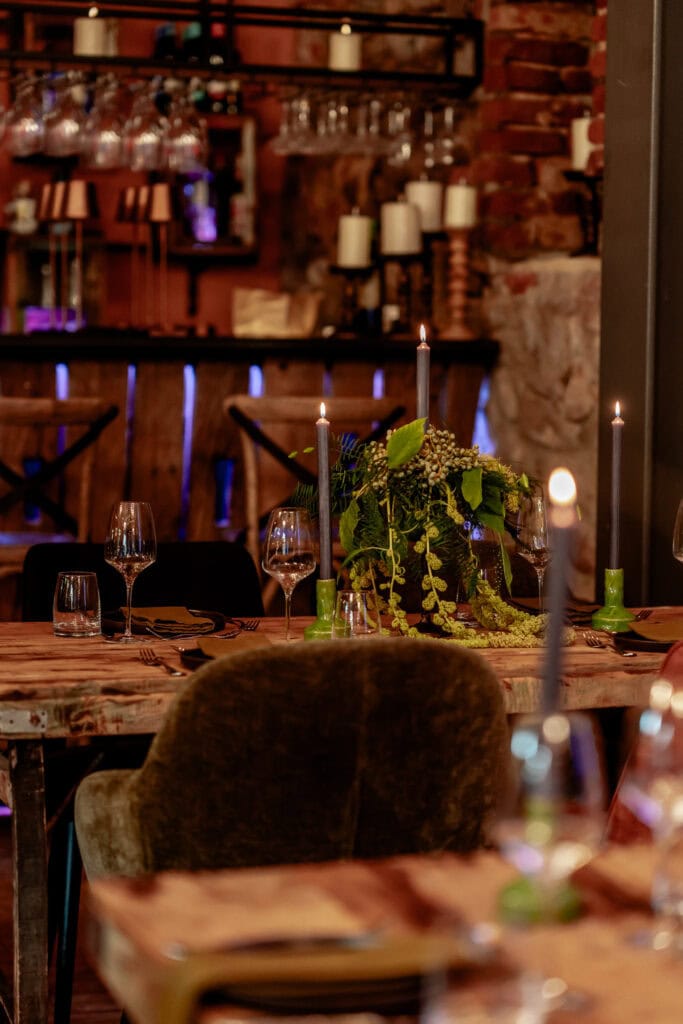Eleganter Esstisch mit Kerzen, Blumen und Wein in gemütlichem Restaurantambiente.