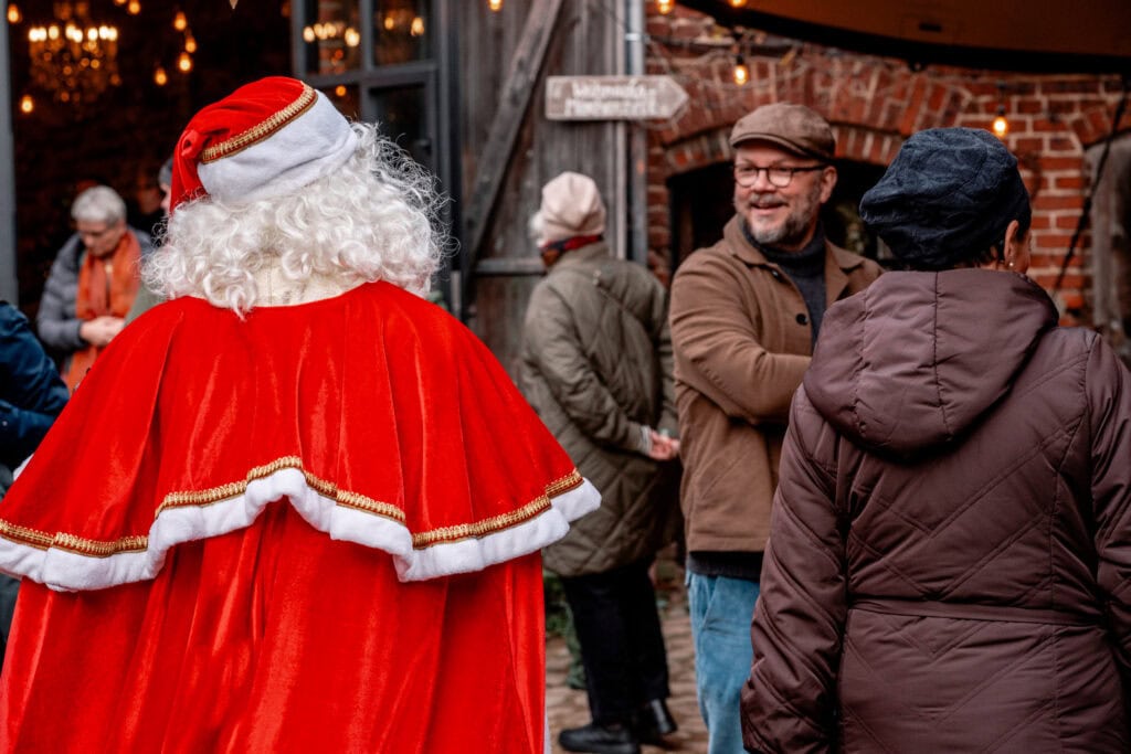Mann im Gespräch mit Santa Claus bei Weihnachtsveranstaltung in Berlin.