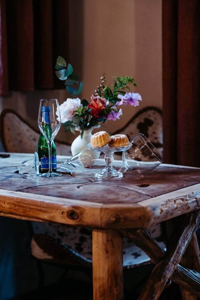 Blumen, Kuchen und Wasserflasche auf rustikalem Holztisch bei Gut Leben Berlin.