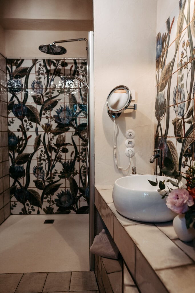 Modern Badezimmer mit floralem Wandmosaik und freistehender Waschschüssel.